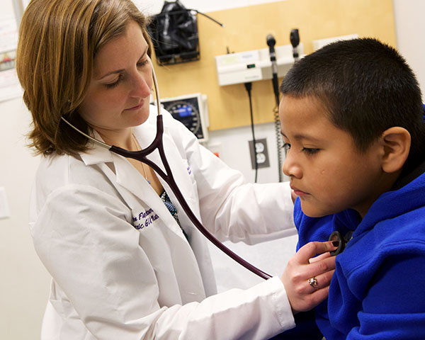 Doctor checking young patient's heart beat with stethoscope.