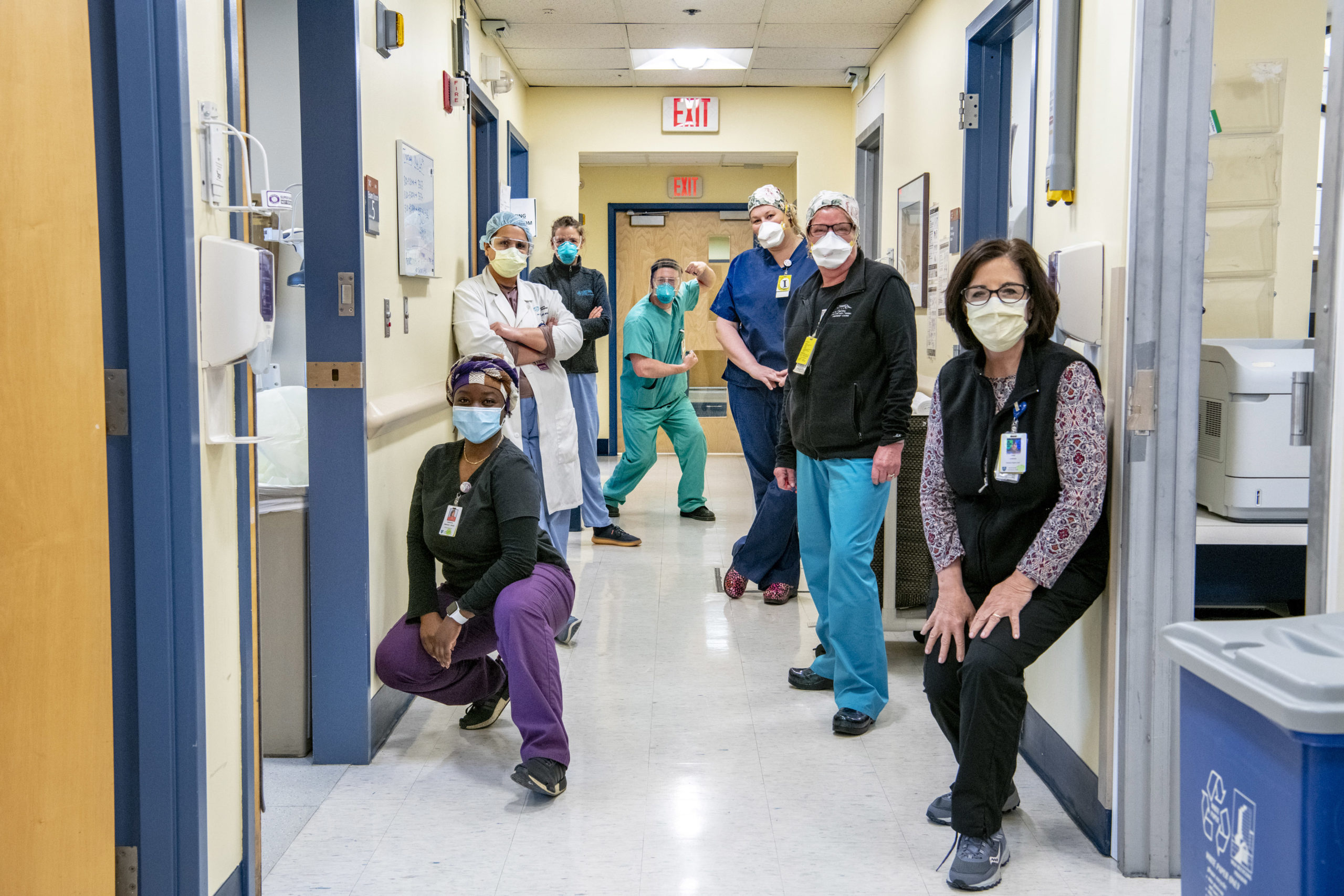 Doctors and nurses wearing masks looking at camera in a Mass General hallway